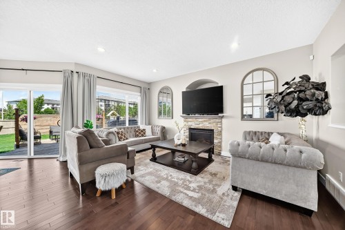 Spacious living area featuring rich wood-finish flooring and a stone-accented fireplace - 13724 166 Avenue Nw, Edmonton, AB 