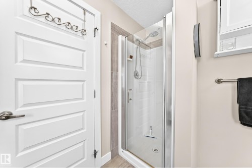 Enclosed shower with clear glass door and light-toned wall tiling - 13724 166 Avenue Nw, Edmonton, AB 