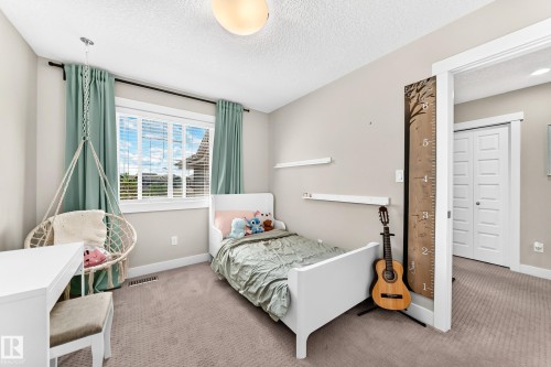 Carpeted room featuring a large window with blinds and drapes, white trim, and a white interior door - 13724 166 Avenue Nw, Edmonton, AB 