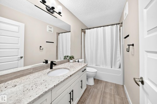 Bathroom featuring a white vanity with a speckled countertop, a matte black faucet, and a large mirror - 13724 166 Avenue Nw, Edmonton, AB 