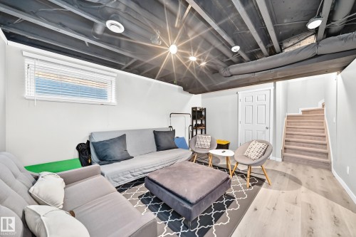 Finished lower level featuring light-toned flooring, recessed lighting, a white paneled door, and a staircase with carpeted treads - 13724 166 Avenue Nw, Edmonton, AB 
