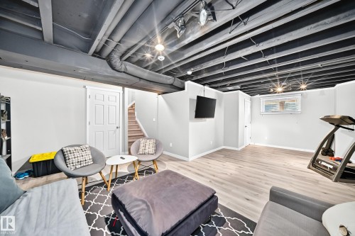 Finished lower level featuring light wood-finish flooring, recessed lighting, painted exposed ceiling joists, white trim, and a white six-panel door - 13724 166 Avenue Nw, Edmonton, AB 