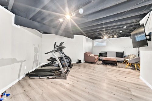 Finished basement space featuring light wood-finish flooring, white walls, and a dark exposed beam ceiling - 13724 166 Avenue Nw, Edmonton, AB 