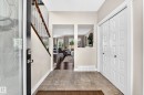 Entryway featuring tile flooring, a multi-paneled bifold closet door, and a staircase with wood railing and metal balusters - 13724 166 Avenue Nw, Edmonton, AB 