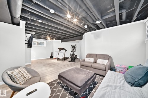 Finished lower level featuring light wood-finish flooring, recessed lighting, painted exposed ceiling joists, white walls, and a window providing natural light - 13724 166 Avenue Nw, Edmonton, AB 