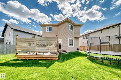 Expansive rear yard featuring a large wooden deck with privacy screening, a spacious grassy area, and rear exterior access - 13724 166 Avenue Nw, Edmonton, AB 