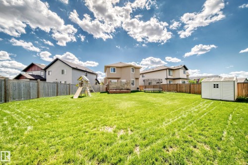Expansive green lawn surrounded by a privacy fence, featuring a wooden deck, and a detached storage shed - 13724 166 Avenue Nw, Edmonton, AB 