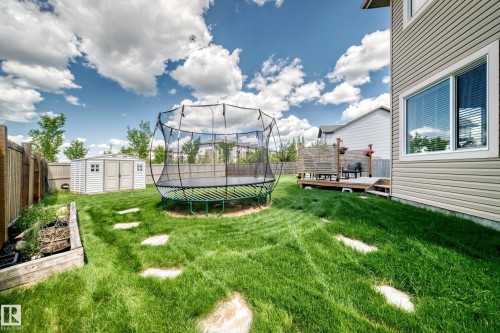 Expansive backyard featuring a green lawn, stepping stones, a raised garden bed, and a storage shed - 13724 166 Avenue Nw, Edmonton, AB 