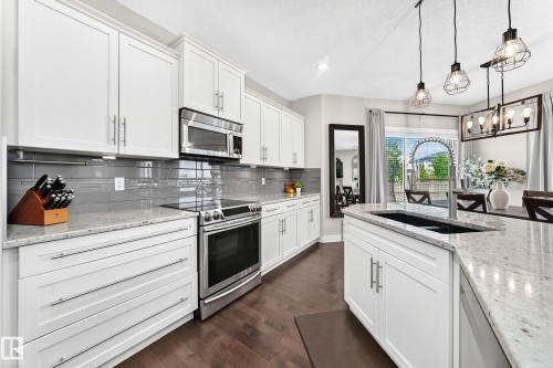 Gourmet kitchen featuring white cabinetry, stainless steel appliances, granite countertops, and a gray subway tile backsplash - 13724 166 Avenue Nw, Edmonton, AB 