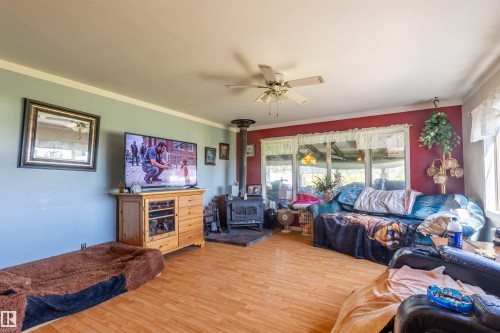 Living area featuring wood-finish flooring, a ceiling fan, and a wood-burning stove with a black pipe - 551027 Range Road 193, Rural Lamont County, AB 