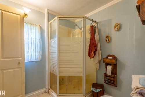Corner shower enclosure with frosted glass panels, light blue vertical paneling, crown molding, and a wall-mounted light fixture - 551027 Range Road 193, Rural Lamont County, AB 