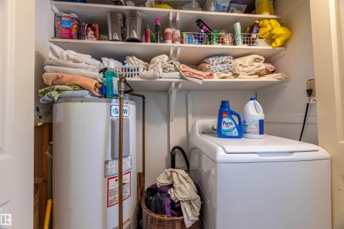 Dedicated laundry area featuring a white top-load washing machine, built-in shelving, and a water heater - 551027 Range Road 193, Rural Lamont County, AB 