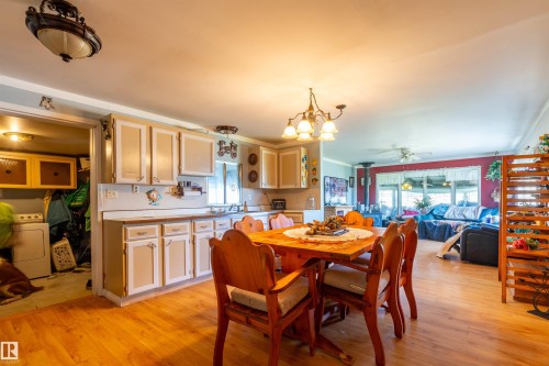 Open concept living area featuring wood-finish flooring, a kitchen with light-toned cabinetry and a countertop, and an adjacent dining space with a chandelier - 551027 Range Road 193, Rural Lamont County, AB 