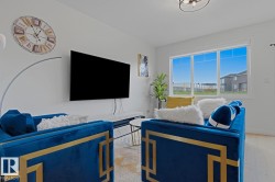 Bright living area featuring light wood-finish flooring, a contemporary ceiling light fixture, and a large multi-pane window - 