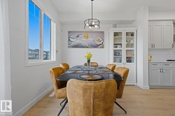 Dining area featuring light wood-finish flooring, a contemporary chandelier, and a large window - 