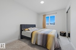 Bright room featuring neutral carpeting, white walls, a large window with white trim, and a full-height mirrored closet - 