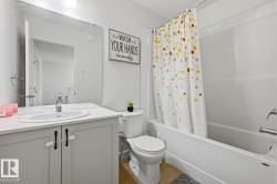 Full bathroom featuring an integrated shower-tub combination, a vanity with a white countertop and undermount sink, a large wall-mounted mirror, and wood-finish flooring - 
