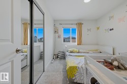 Bright room featuring two windows with natural light, a mirrored sliding closet door, white walls, and gray carpet - 