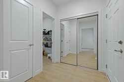 Hallway featuring wood-finish flooring, white paneled doors, and a mirrored closet - 