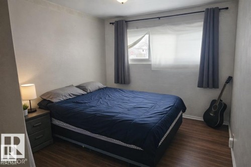 Bedroom featuring wood-finish flooring, a window with roller blinds and drapery, and a neutral wall finish - 13204 131A Avenue Nw, Edmonton, AB - Indoor Photo Showing Bedroom