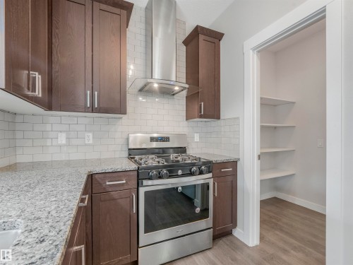 Modern kitchen featuring dark wood-finish cabinetry, light speckled countertops, and a subway tile backsplash - 20507 99 Avenue, Edmonton, AB - Indoor Photo Showing Kitchen