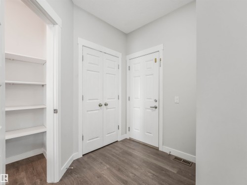 Entryway featuring wood-finish flooring, a built-in shelving unit, white paneled doors, and contemporary wall color - 20507 99 Avenue, Edmonton, AB - Indoor Photo Showing Other Room