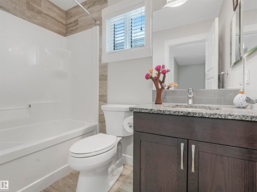 Bathroom featuring a white tub/shower combination with a wood-finish tile surround - 20507 99 Avenue, Edmonton, AB - Indoor Photo Showing Bathroom