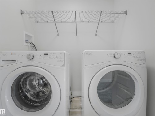 Laundry area with a wall-mounted wire shelving unit and light-toned flooring - 20507 99 Avenue, Edmonton, AB - Indoor Photo Showing Laundry Room