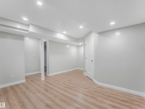Spacious interior featuring wood-finish flooring, recessed lighting, neutral paint, white trim, and a paneled door - 20507 99 Avenue, Edmonton, AB - Indoor Photo Showing Other Room