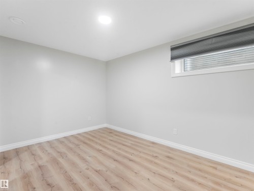 Room with light wood-finish flooring, white baseboards, light gray walls, and a single window with a gray privacy blind - 20507 99 Avenue, Edmonton, AB - Indoor Photo Showing Other Room