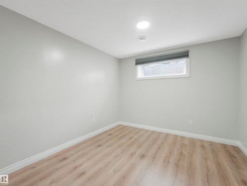 Bright room featuring recessed lighting, a window with a roller shade, light gray walls, white baseboards, and wood-finish flooring - 20507 99 Avenue, Edmonton, AB - Indoor Photo Showing Other Room