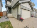 Modern exterior featuring light gray siding, stone accents, a double-panel garage door, concrete front steps, and a concrete pathway - 20507 99 Avenue, Edmonton, AB  - Outdoor With Exterior 