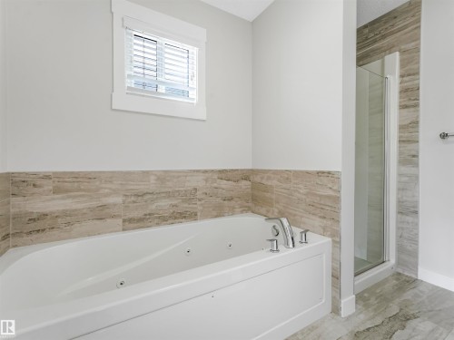 Soaking tub with integrated jets, chrome fixtures, and a tiled surround - 20507 99 Avenue, Edmonton, AB - Indoor Photo Showing Bathroom