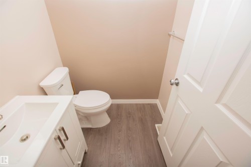 Bathroom featuring a white vanity with brushed nickel hardware, an integrated sink, and a two-piece toilet - 8 Meadowlink Common, Spruce Grove, AB 