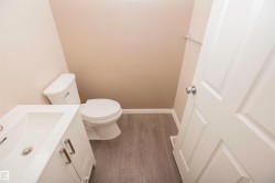 Bathroom featuring a white vanity with brushed nickel hardware, an integrated sink, and a two-piece toilet - 