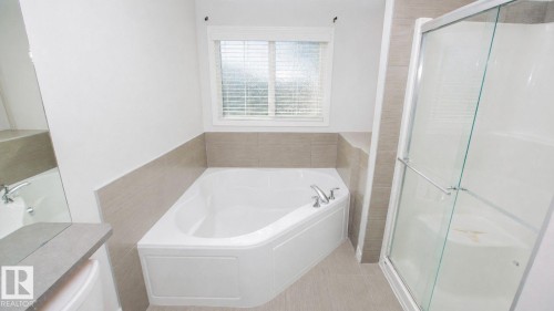 Corner soaking tub with chrome fixtures, complemented by a separate glass-enclosed shower - 8 Meadowlink Common, Spruce Grove, AB 