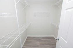 Walk-in closet featuring light gray walls, wood-finish flooring, and white wire shelving - 