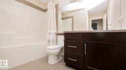 Bathroom featuring a dark wood-finish vanity with chrome hardware, an integrated sink, a large wall mirror, and a combined tub and shower unit - 