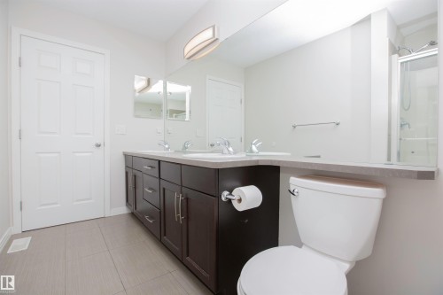 Spacious bathroom featuring a dual-sink vanity with dark wood cabinetry, light-toned countertops, and a full-width mirror - 8 Meadowlink Common, Spruce Grove, AB - Indoor Photo Showing Bathroom