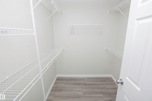 Walk-in closet featuring light gray walls, wood-finish flooring, and white wire shelving - 8 Meadowlink Common, Spruce Grove, AB - Indoor With Storage