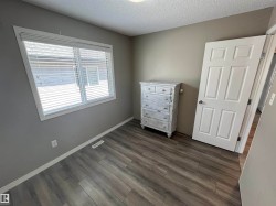 Room featuring wood-finish flooring, a window with blinds, and a paneled door - 