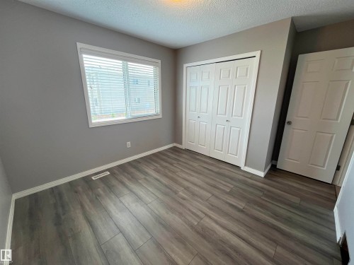 Room featuring wood-finish flooring, neutral grey walls, and white baseboards - 8 Meadowlink Common, Spruce Grove, AB - Indoor Photo Showing Other Room