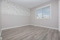 Light gray wood-finish flooring complements soft gray walls and a decorative accent wall featuring a subtle leaf pattern - 