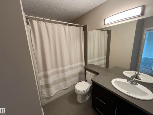 Bathroom featuring a dark wood-finish double vanity with integrated oval sinks, a flush-mount vanity light, and a toilet - 8 Meadowlink Common, Spruce Grove, AB - Indoor Photo Showing Bathroom
