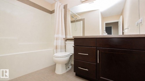 Bathroom featuring a dark wood-finish vanity with chrome hardware, an integrated sink, a large wall mirror, and a combined tub and shower unit - 8 Meadowlink Common, Spruce Grove, AB - Indoor Photo Showing Bathroom