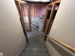 Partially finished basement with framed wall sections, exposed insulation, and a painted concrete floor - 
