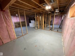 Unfinished basement featuring exposed wood framing, insulated walls, concrete flooring, and exposed ceiling joists - 