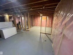 Unfinished basement featuring exposed wood framing, insulated walls, concrete flooring, and exposed ceiling joists - 