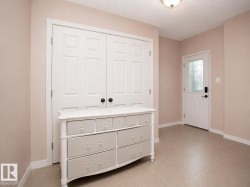 Entryway featuring tiled flooring, a built-in double-door closet with black hardware, and an exterior door with decorative glass paneling - 