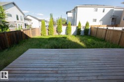 Expansive backyard featuring a wood deck, natural grass, perimeter wood fencing, and mature evergreen plantings - 